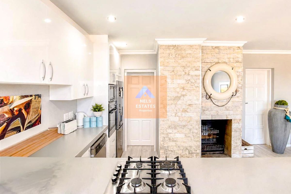 Modern kitchen featuring a central gas hob, built-in appliances, and a striking stone-clad fireplace feature wall, creating a warm and functional culinary space.