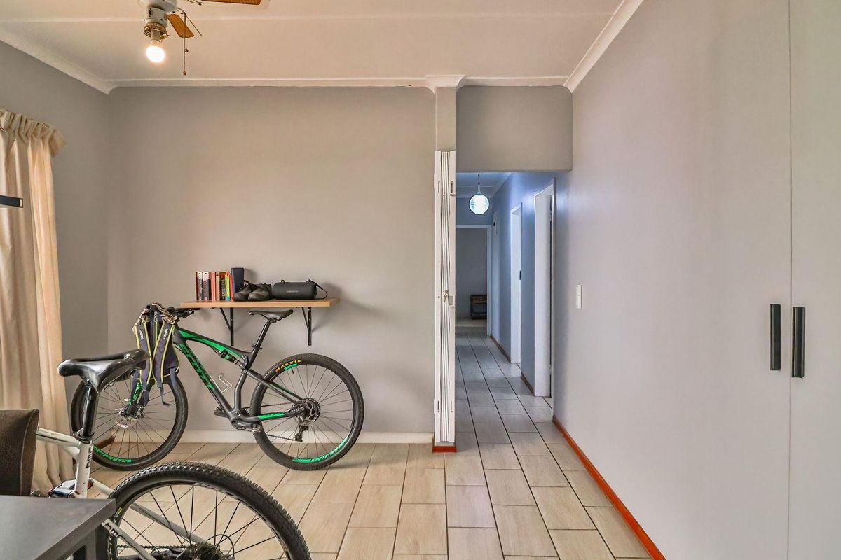 A bedroom featuring tiled flooring, a built-in wardrobe, and a ceiling fan, with direct access to the hallway.