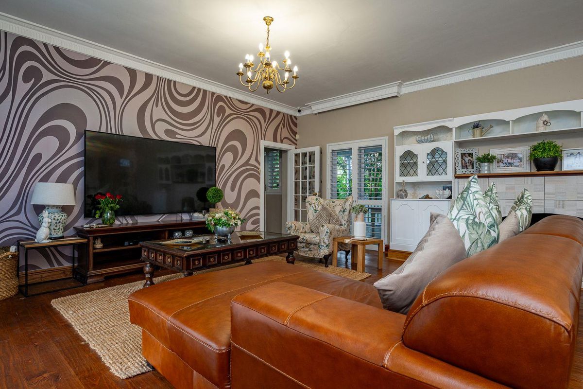 Spacious living room featuring hardwood flooring, decorative crown molding, a built-in display cabinet, and French doors leading to the exterior.