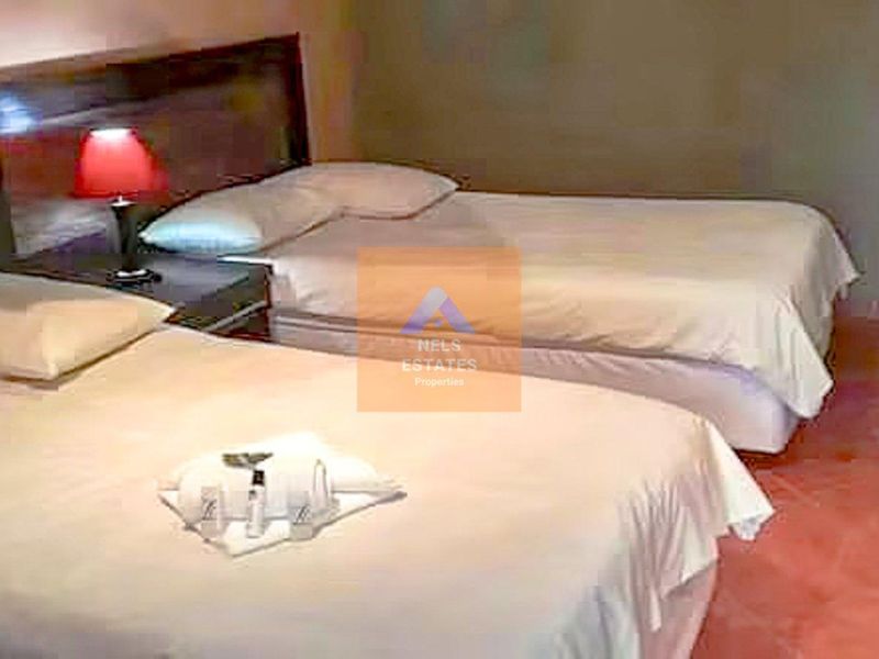 A hotel bedroom featuring a built-in headboard and tiled flooring.