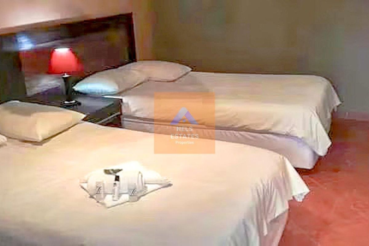 A hotel bedroom featuring a built-in headboard and tiled flooring.