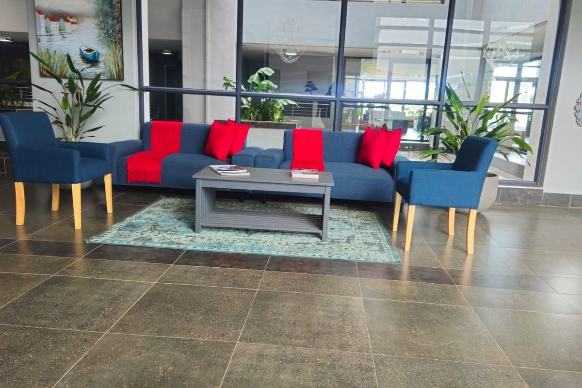 A spacious lobby or communal living area featuring large format floor tiles and expansive glass partitioning, creating an open and bright atmosphere.
