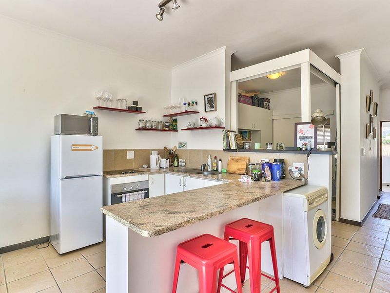 Compact kitchen featuring laminate countertops, built-in oven, electric hob, and tiled flooring, with an open-plan layout connecting to the living area.