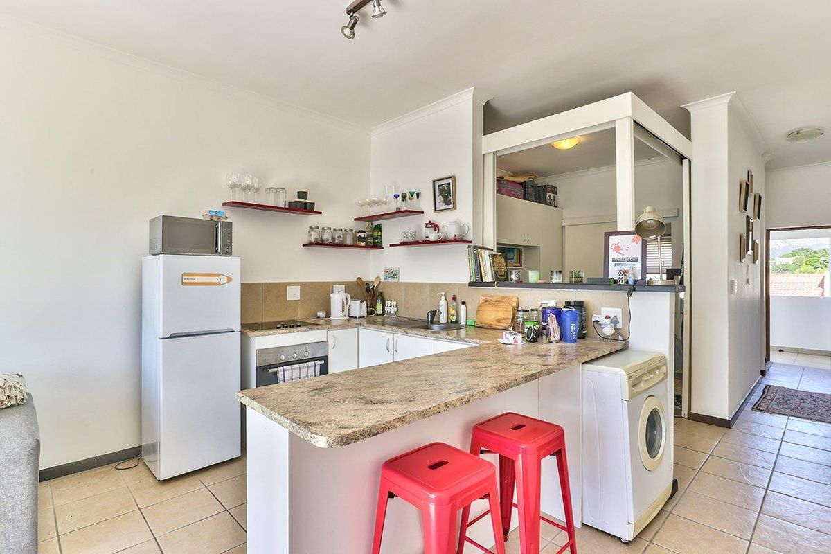 Compact kitchen featuring laminate countertops, built-in oven, electric hob, and tiled flooring, with an open-plan layout connecting to the living area.