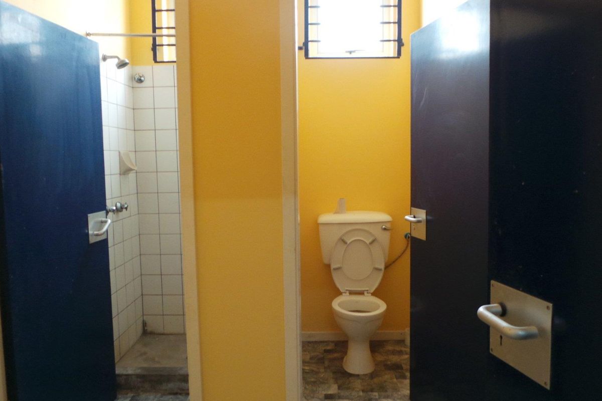 A functional bathroom facility featuring a separate shower cubicle with tiled walls and a private toilet area with standard sanitary ware.