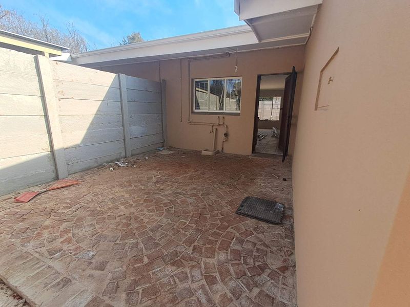A rear courtyard area featuring cobblestone paving, a precast concrete boundary wall, and direct access to the interior through an external door.