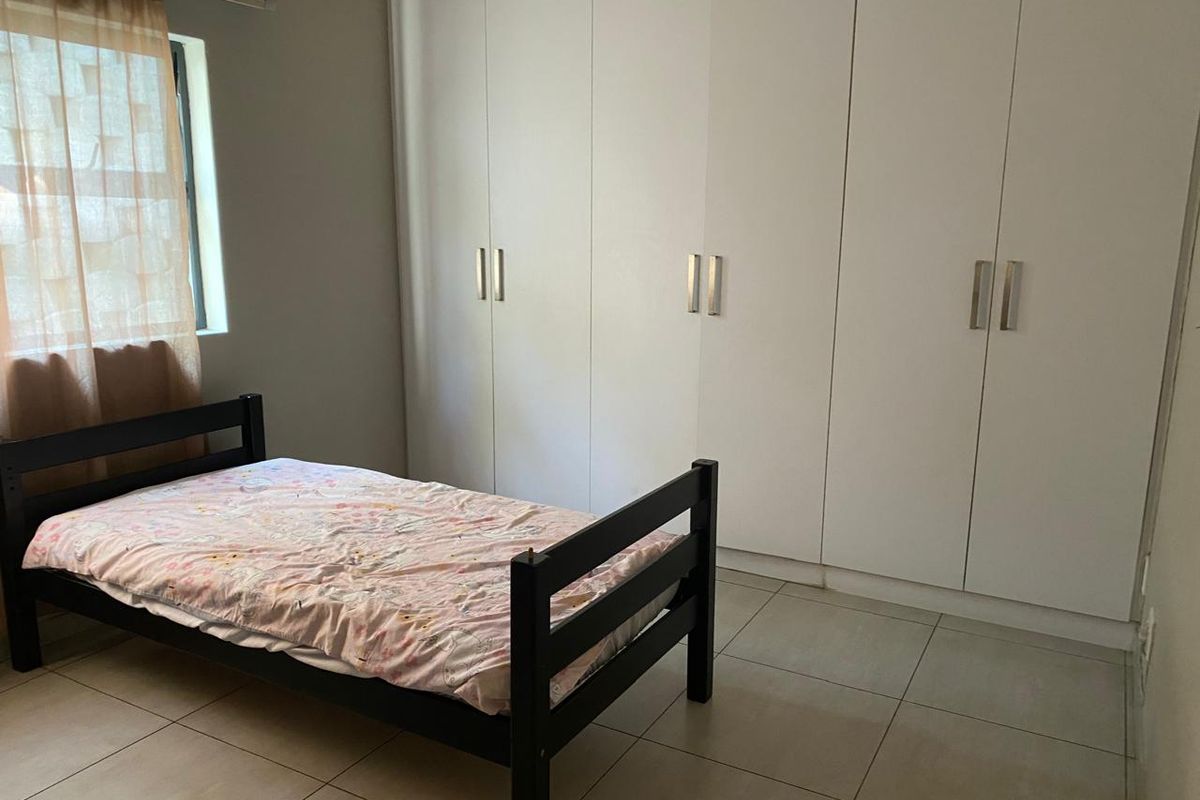 A bedroom featuring neutral tiled flooring and extensive white built-in cupboards providing ample storage space.
