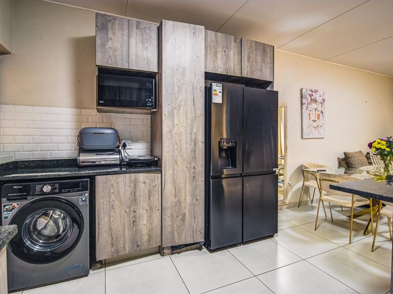 Modern kitchen featuring wood-grain cabinetry, granite countertops, subway tile backsplash, and integrated appliance housing, seamlessly flowing into the dining area.