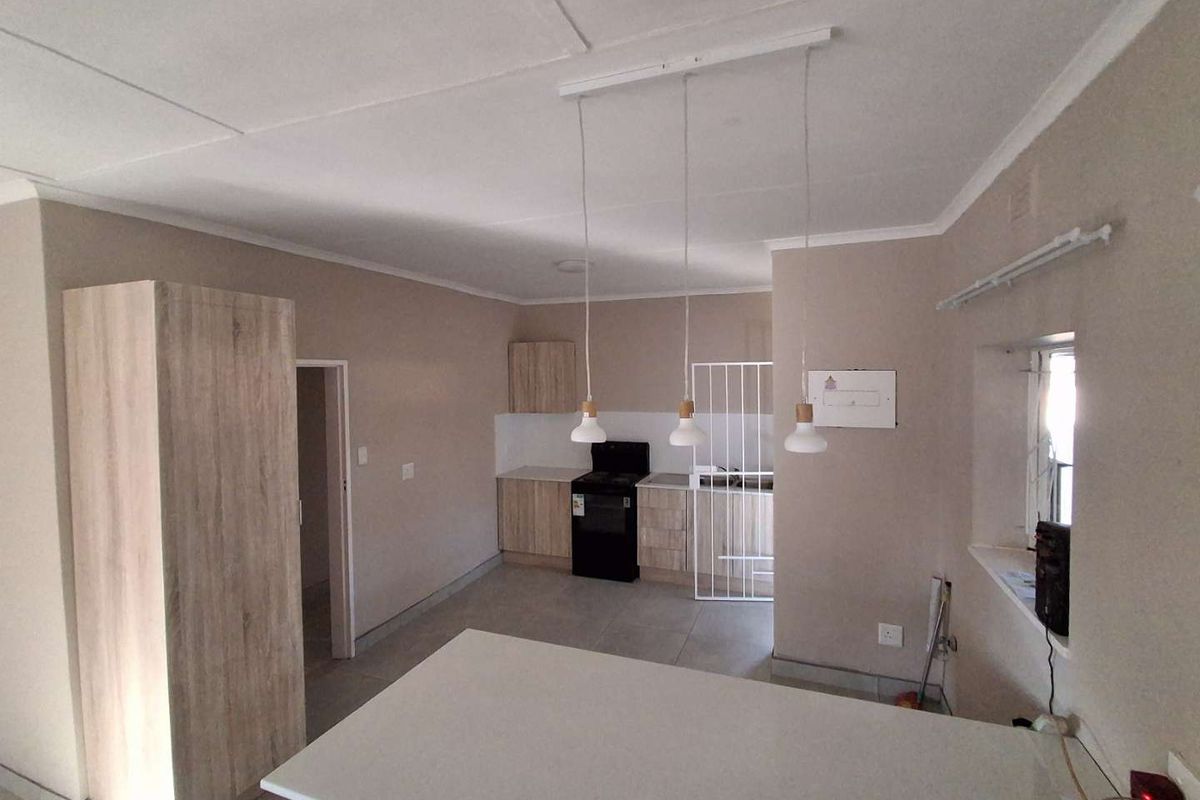 A functional kitchen featuring light wood-finish cabinetry, tiled flooring, and pendant lighting, offering a clean and neutral space ready for personalization.