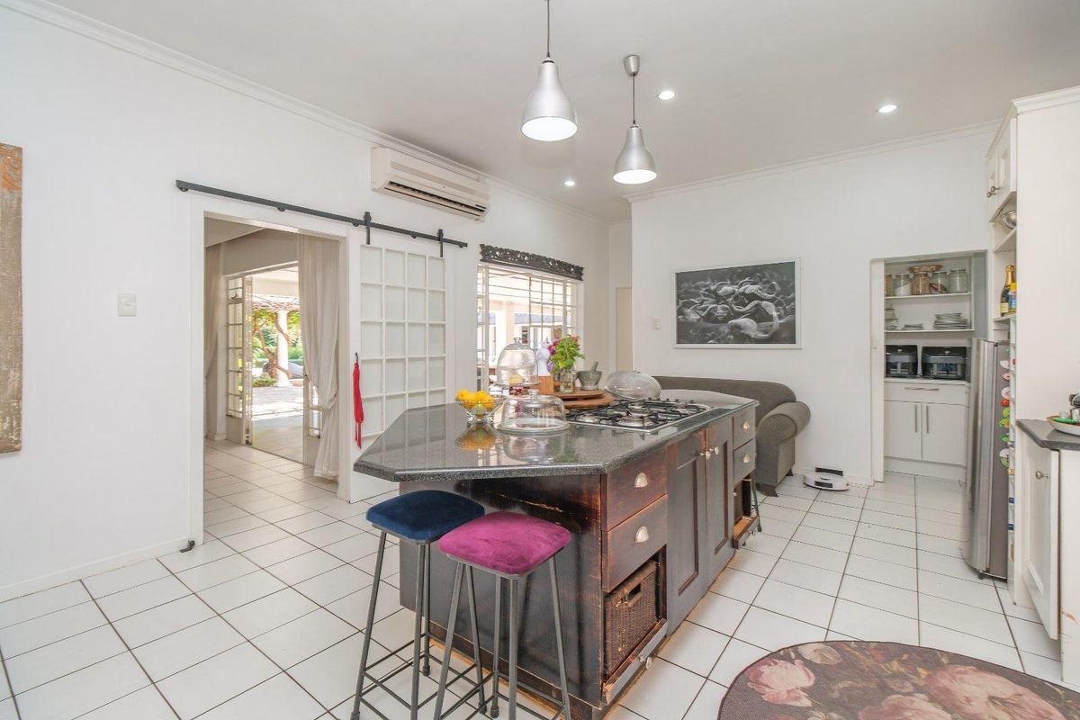 Spacious kitchen featuring a central island with a gas cooktop, granite countertops, tiled flooring, and a convenient walk-in pantry area.