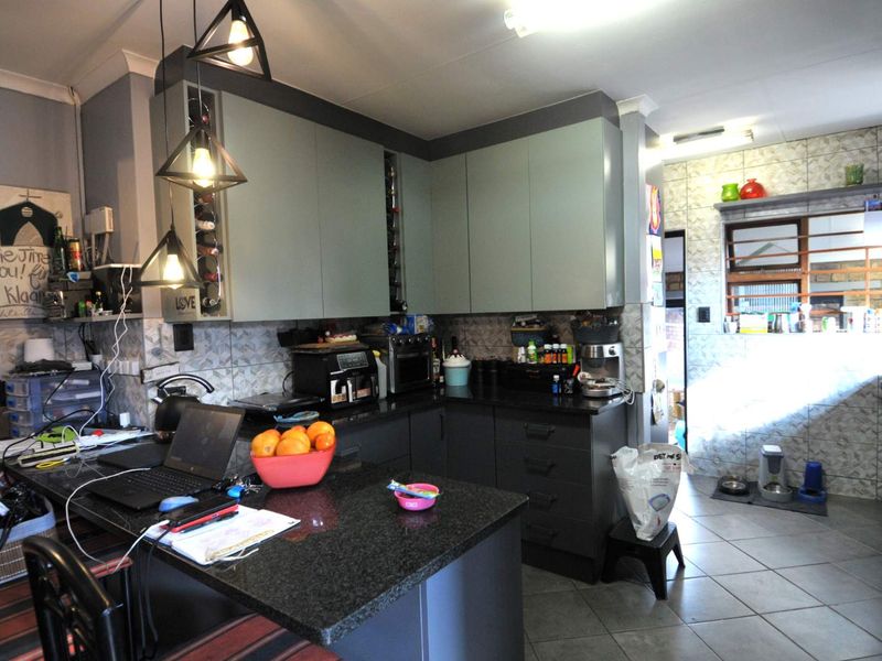 A functional kitchen featuring modern grey cabinetry, granite countertops, and tiled finishes, offering a practical layout for daily meal preparation.