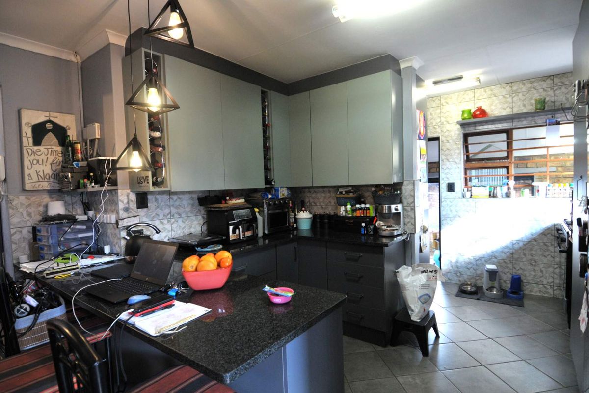 A functional kitchen featuring modern grey cabinetry, granite countertops, and tiled finishes, offering a practical layout for daily meal preparation.