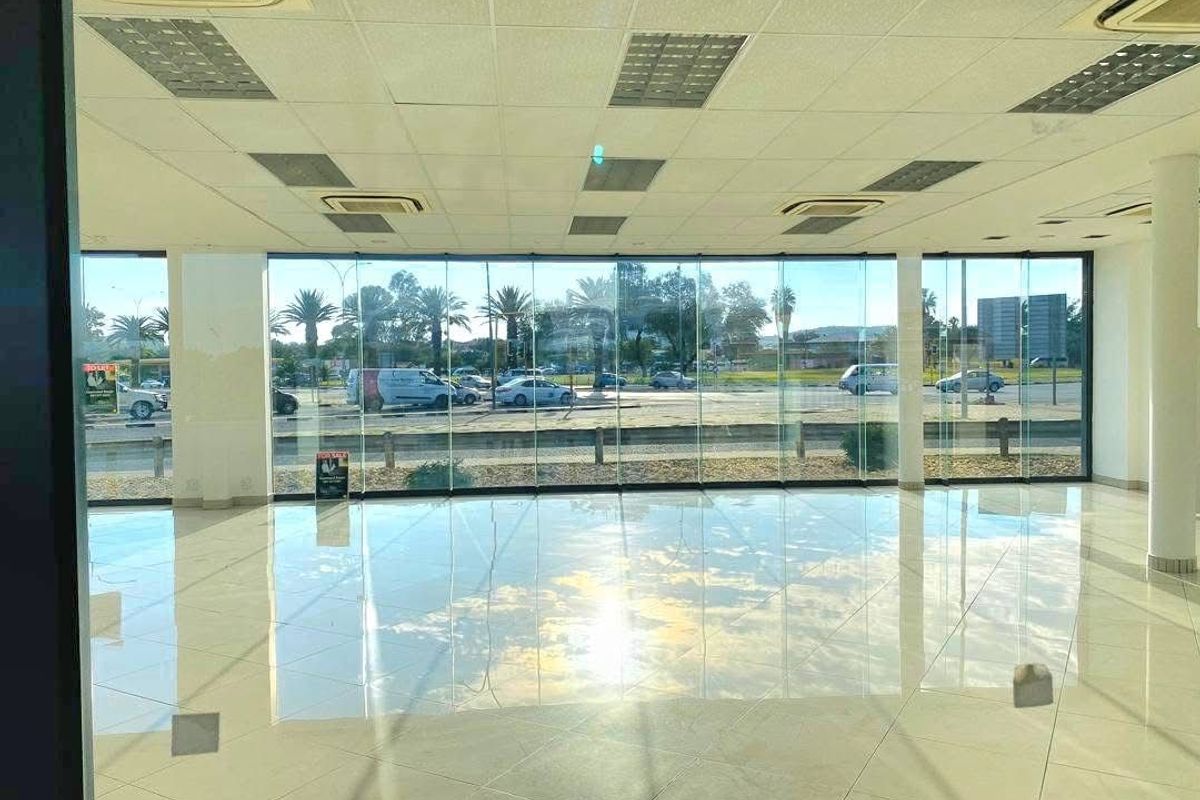 Spacious open-plan retail area featuring floor-to-ceiling glass windows, tiled flooring, and integrated ceiling air conditioning units, offering excellent visibility and natural light.