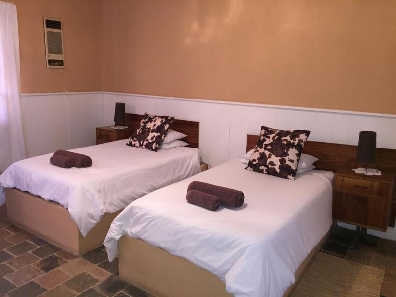 A bedroom featuring stone tile flooring, wainscoting, and a wall-mounted air conditioning unit.