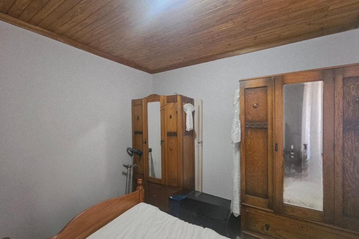 A bedroom featuring a distinctive timber-paneled ceiling and neutral wall finishes, providing a classic and cozy atmosphere.