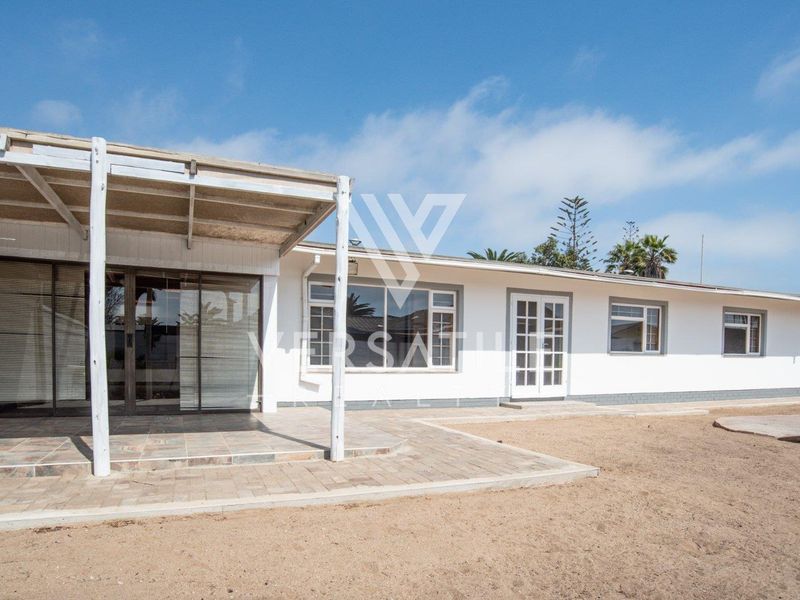 Rear view of the property featuring a covered tiled patio, sliding glass doors, and french doors leading into the home with a large sandy yard.