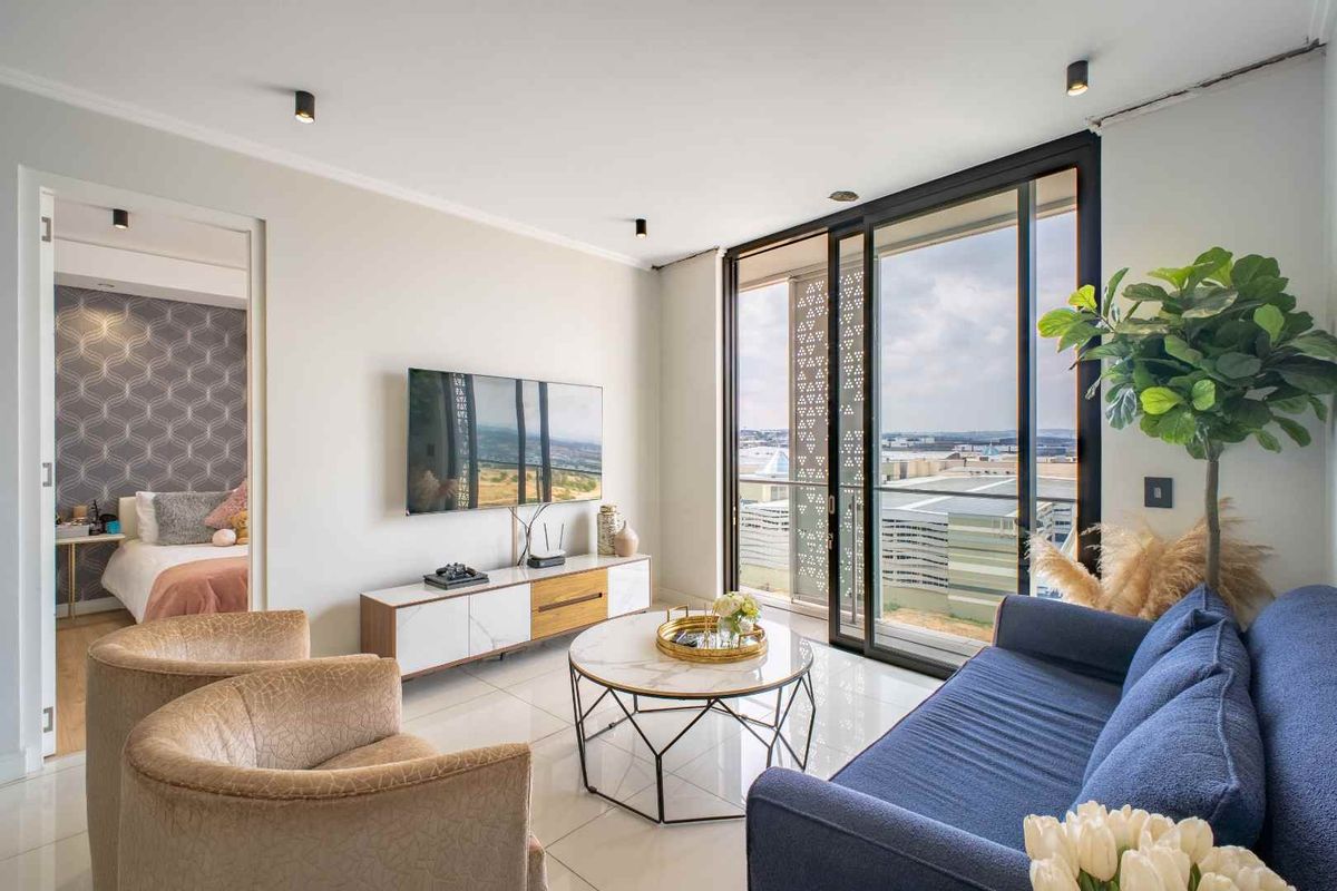 Modern living room featuring large sliding glass doors leading to a balcony, polished floor tiles, and recessed ceiling lighting.