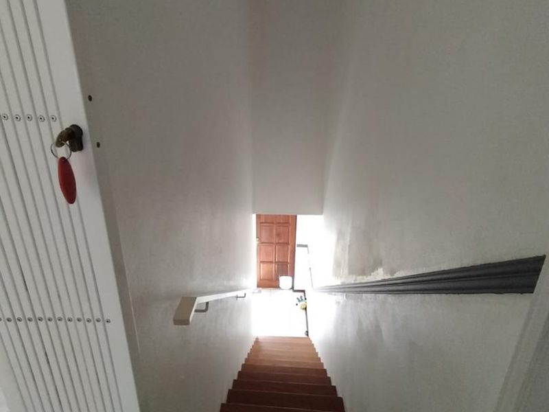 A narrow staircase hallway featuring a handrail and visible wall wear, requiring maintenance and cosmetic updates.