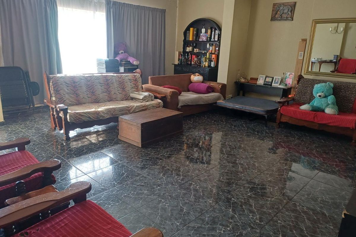 A spacious living room featuring dark marble-effect tiled flooring and large windows with curtain rails.