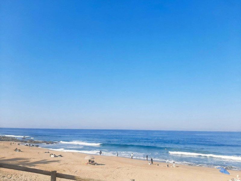 A scenic view of the coastline featuring a sandy beach and ocean waves, highlighting the property's proximity to the sea.