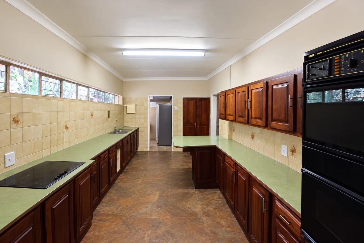 Spacious kitchen featuring extensive wooden cabinetry, laminate countertops, built-in double oven, electric hob, and tiled backsplash with a functional layout.