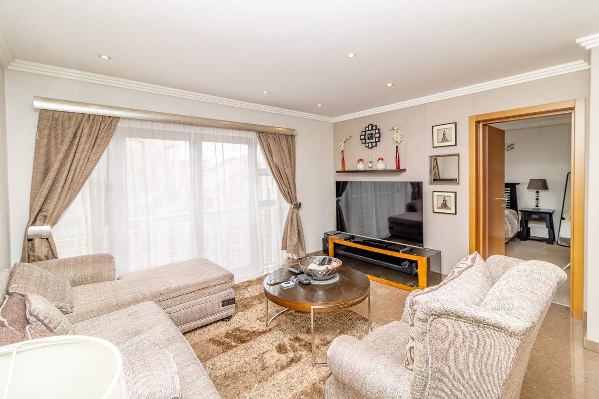 A comfortable living room featuring recessed ceiling lighting, tiled flooring, and large sliding glass doors that provide access to an outdoor balcony area.