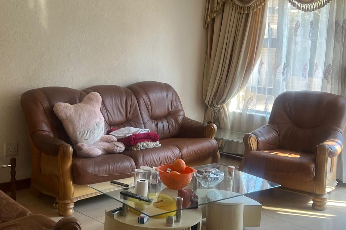 A living room area featuring tiled flooring and window treatments, providing a functional space for relaxation.