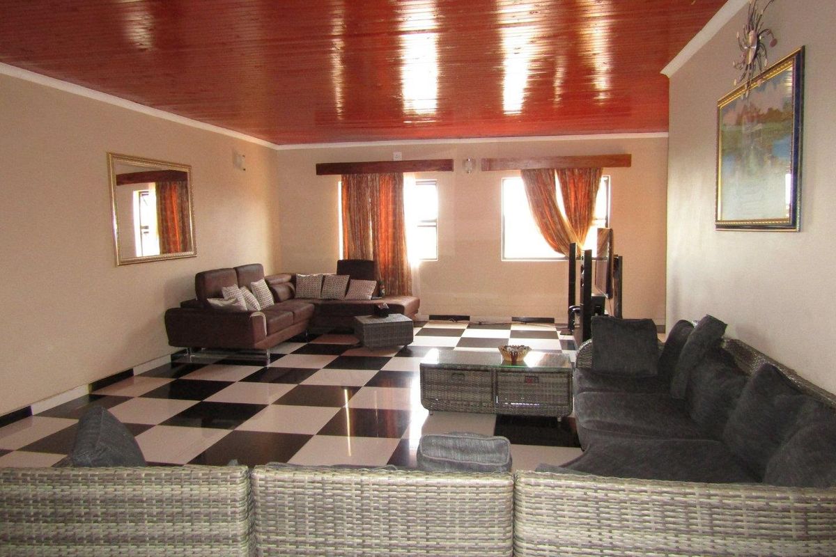 Spacious living room featuring a high-gloss timber-look ceiling and a distinctive black and white checkered tiled floor.