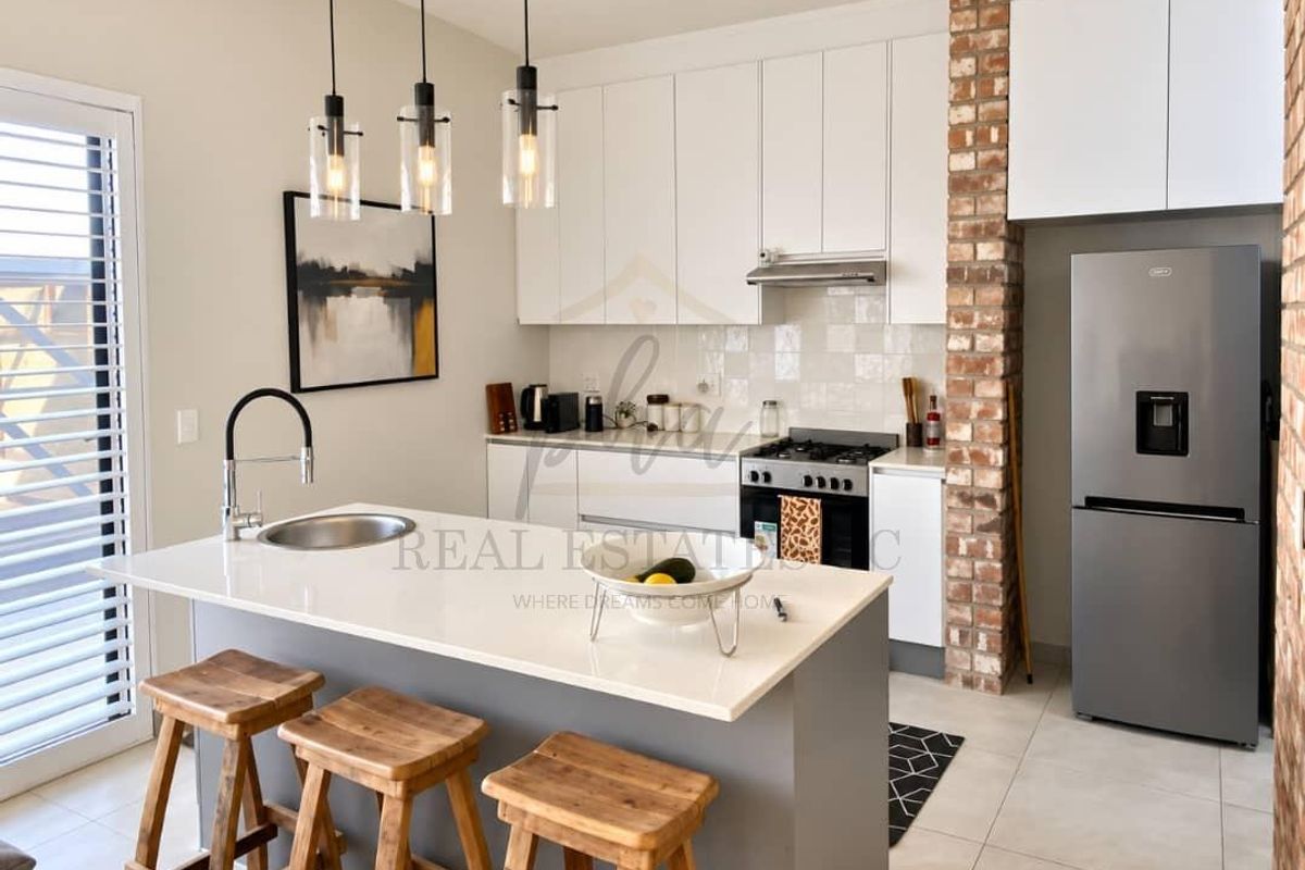 Modern kitchen featuring a central island with quartz countertops, exposed brick accents, built-in appliances, and stylish pendant lighting in an open-plan layout.
