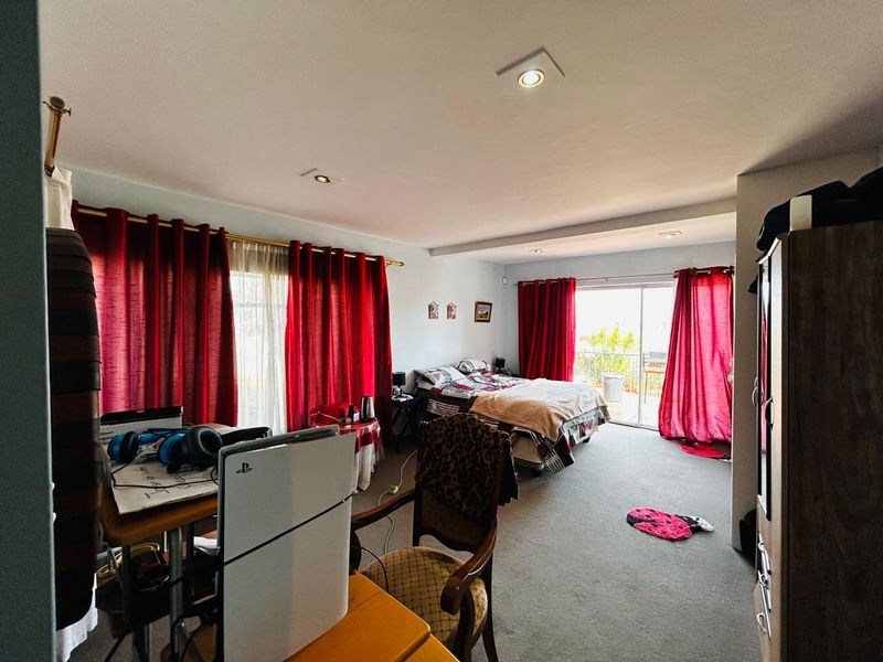 Spacious bedroom featuring carpet flooring, recessed downlights, and a sliding glass door providing access to an outdoor area.