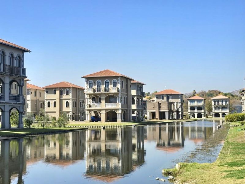 A scenic view of multi-story residential apartment buildings situated along a tranquil canal, featuring classic architectural details and well-maintained landscaped grounds.