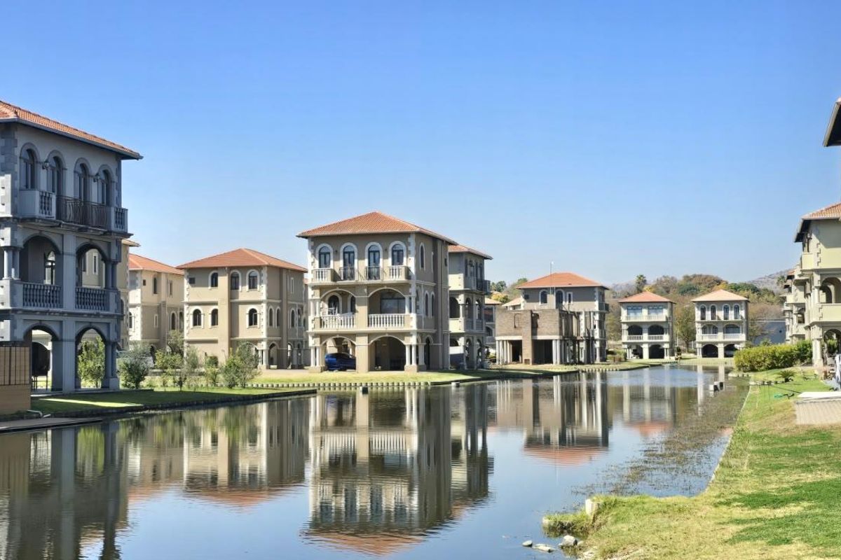 A scenic view of multi-story residential apartment buildings situated along a tranquil canal, featuring classic architectural details and well-maintained landscaped grounds.