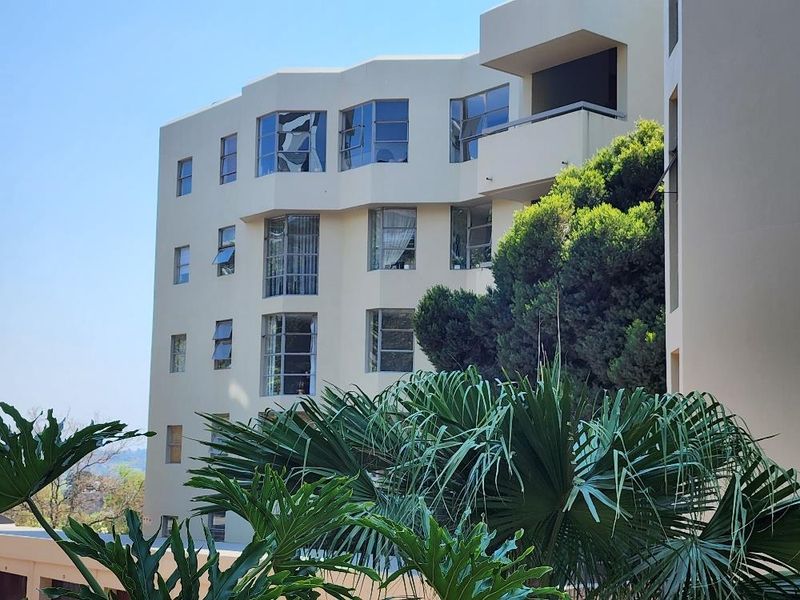 Exterior view of a multi-story apartment building facade featuring multiple windows and balconies set against a clear sky.