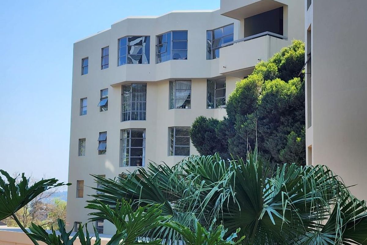 Exterior view of a multi-story apartment building facade featuring multiple windows and balconies set against a clear sky.