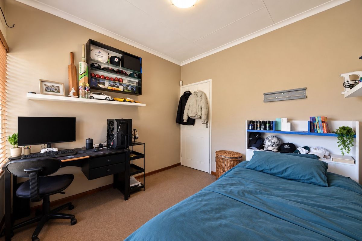 A functional bedroom featuring carpet flooring, neutral wall tones, and built-in shelving, providing a comfortable and practical living space.
