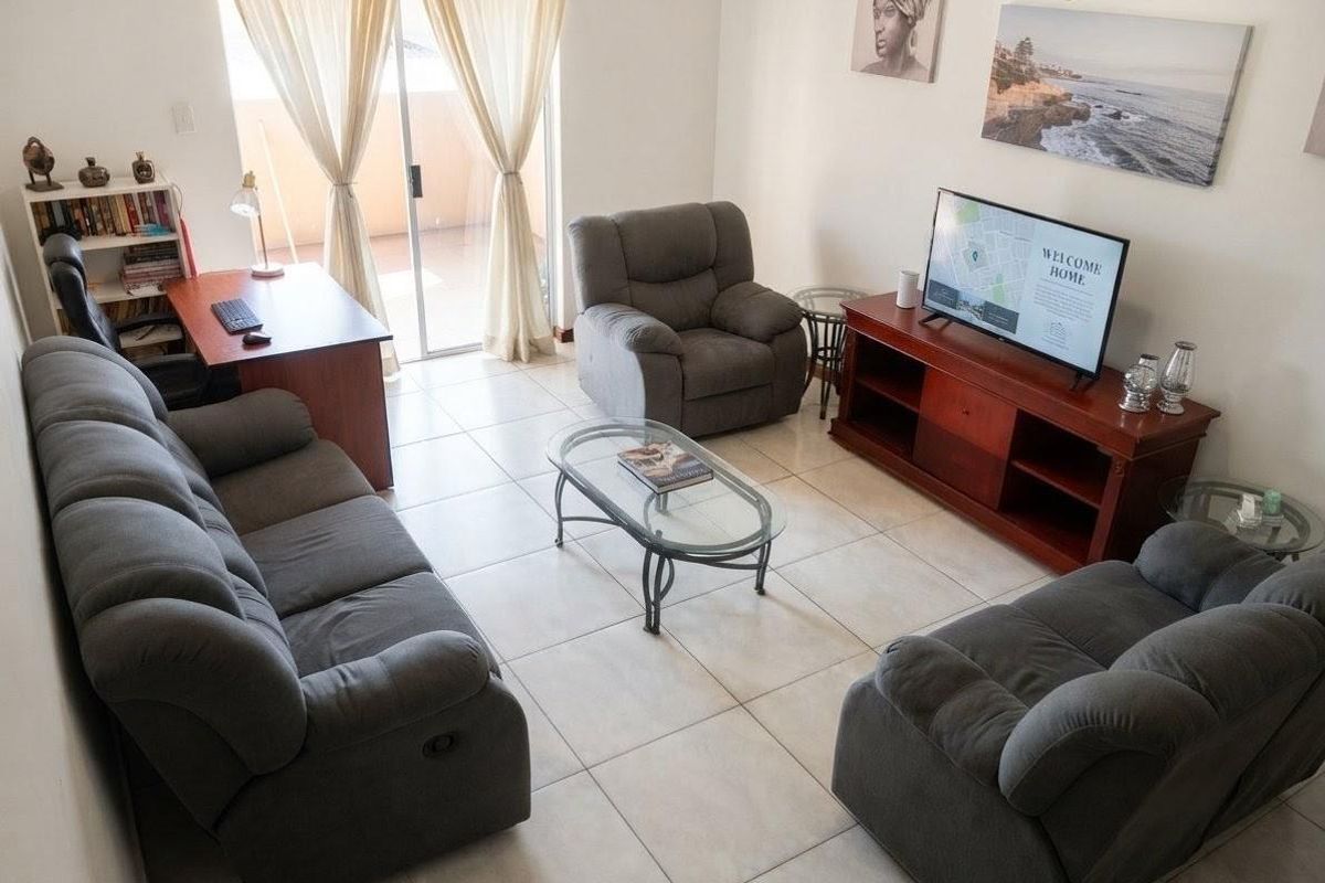 A comfortable living room featuring tiled flooring and a sliding glass door providing access to an outdoor area.