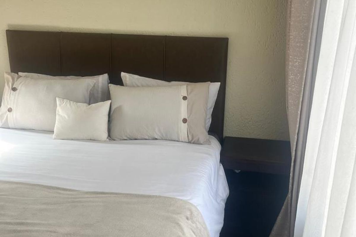A bedroom featuring dark wood flooring and a neutral wall finish, providing a comfortable and functional sleeping space.