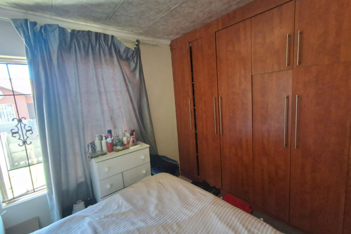 Bedroom featuring floor-to-ceiling built-in wooden cupboards and security bars on the window.