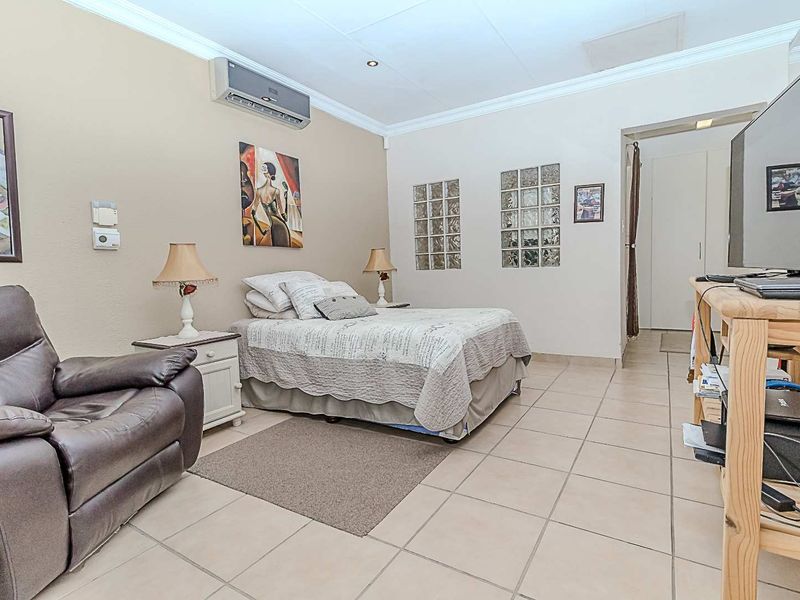 A bedroom featuring tiled flooring, glass block windows for natural light, and a wall-mounted air conditioning unit.