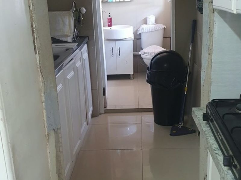 A kitchen area showing built-in cabinetry and a gas hob, leading into an adjacent bathroom. The space requires finishing work on the door frame.
