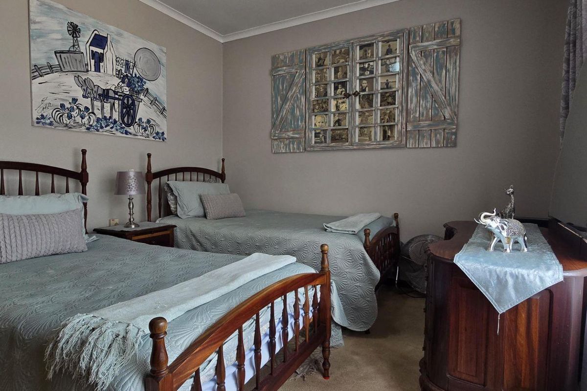 A well-maintained bedroom featuring neutral wall tones, carpeted flooring, and ample space for two beds.
