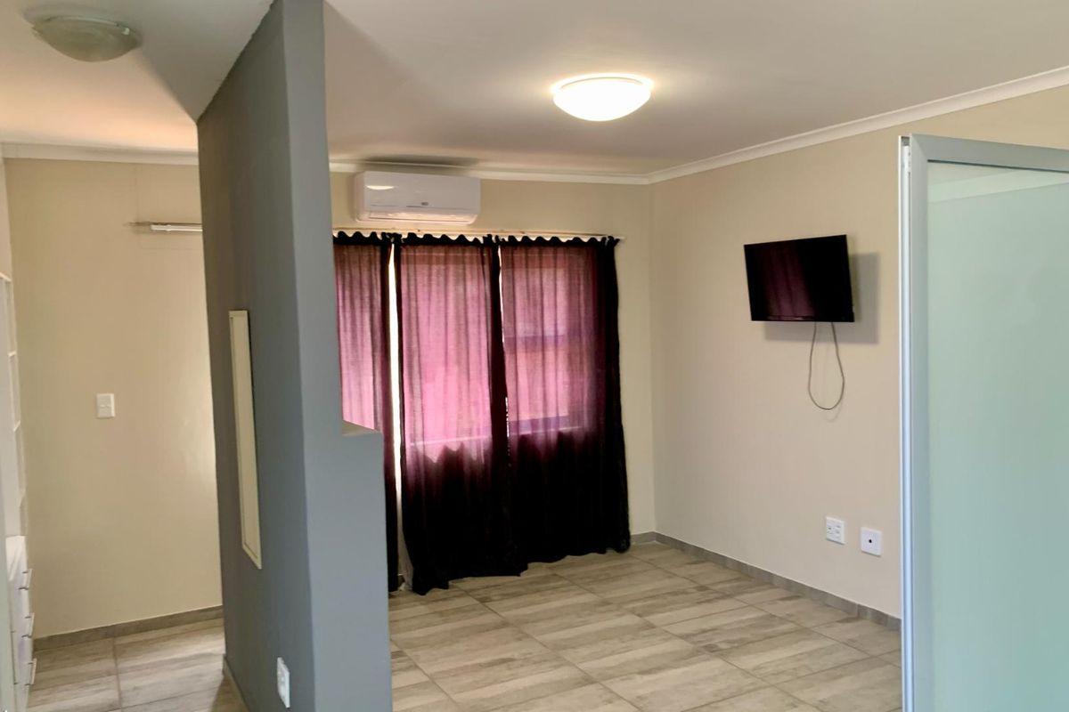 A bedroom featuring tiled flooring, a wall-mounted air conditioning unit, and a partition wall creating a semi-private layout.