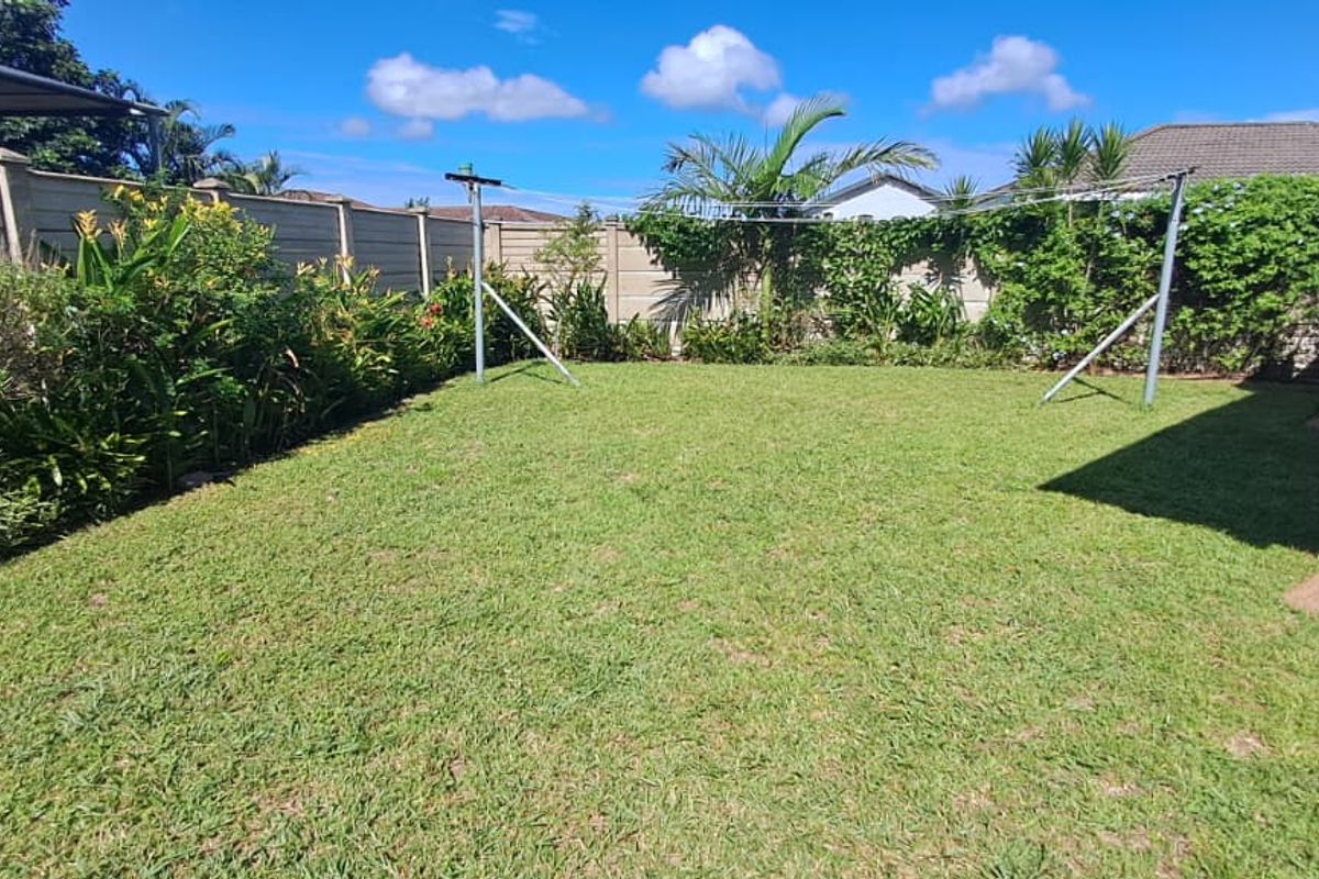 A well-maintained private rear garden featuring a lush lawn, perimeter boundary walls, and a fixed outdoor washing line.