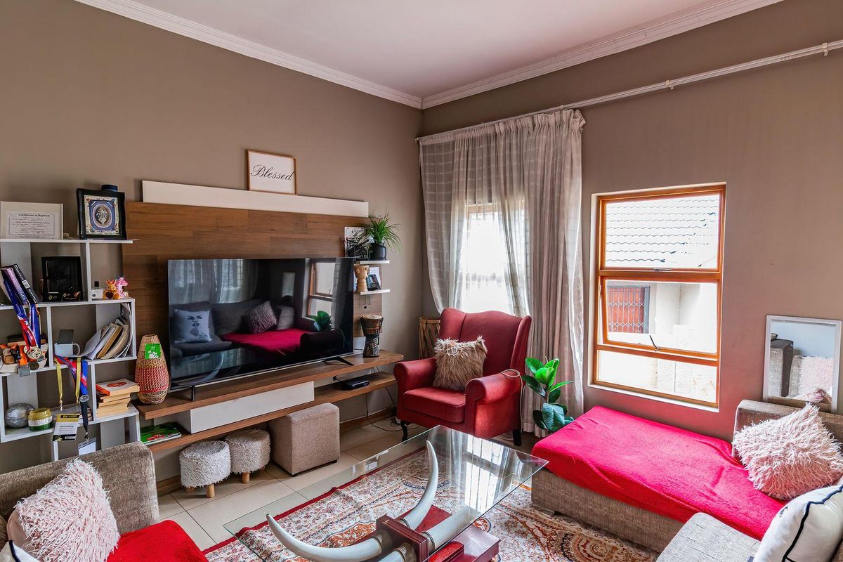 A comfortable living room featuring tiled flooring, a built-in wooden media console, and large windows that provide natural light.