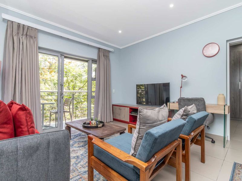 A bright and well-maintained living room featuring tiled floors, recessed lighting, and a sliding glass door providing access to a private balcony.