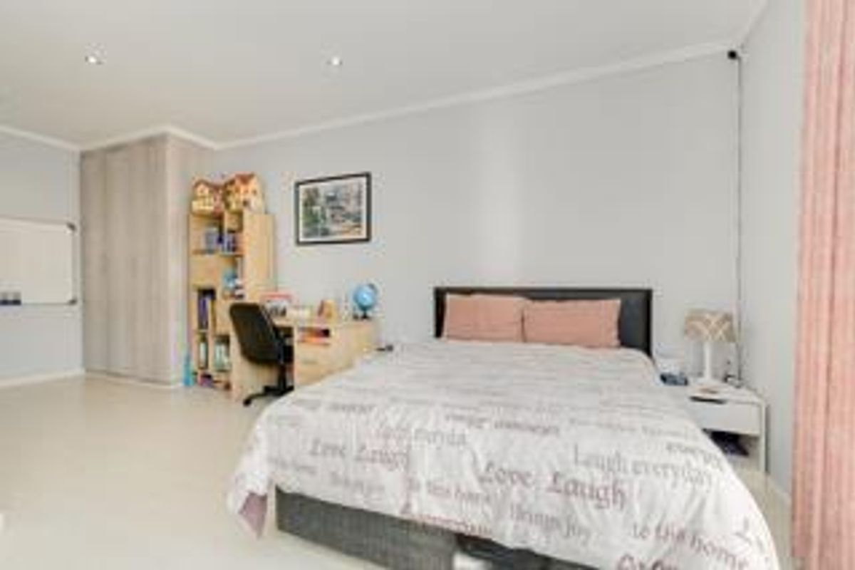 A well-maintained bedroom featuring built-in cupboards, recessed downlighting, and neutral wall finishes, providing a comfortable and functional living space.