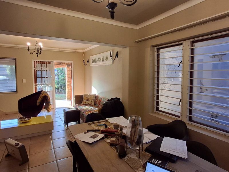 Open plan living and dining area featuring tiled floors, security bars on windows, and direct access to an outdoor patio through a sliding glass door.