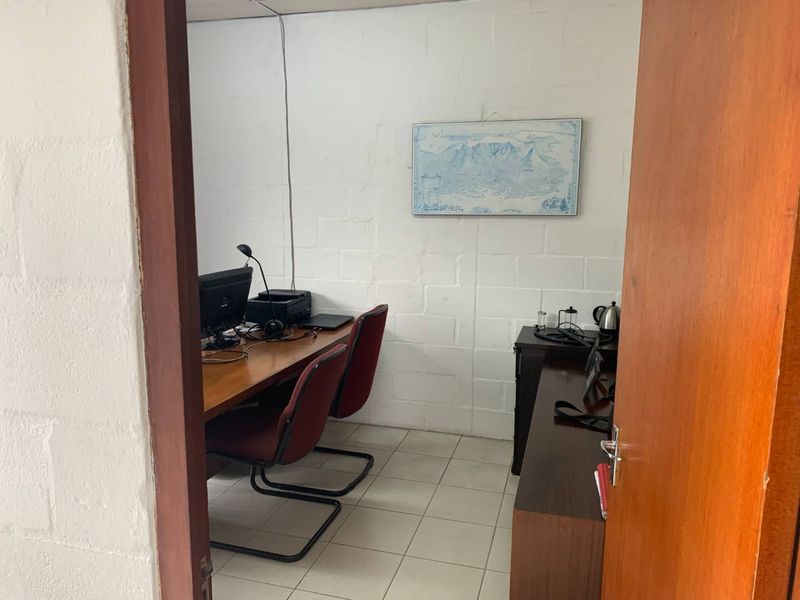 A functional office space featuring tiled flooring and painted concrete block walls, currently utilized as a workspace.