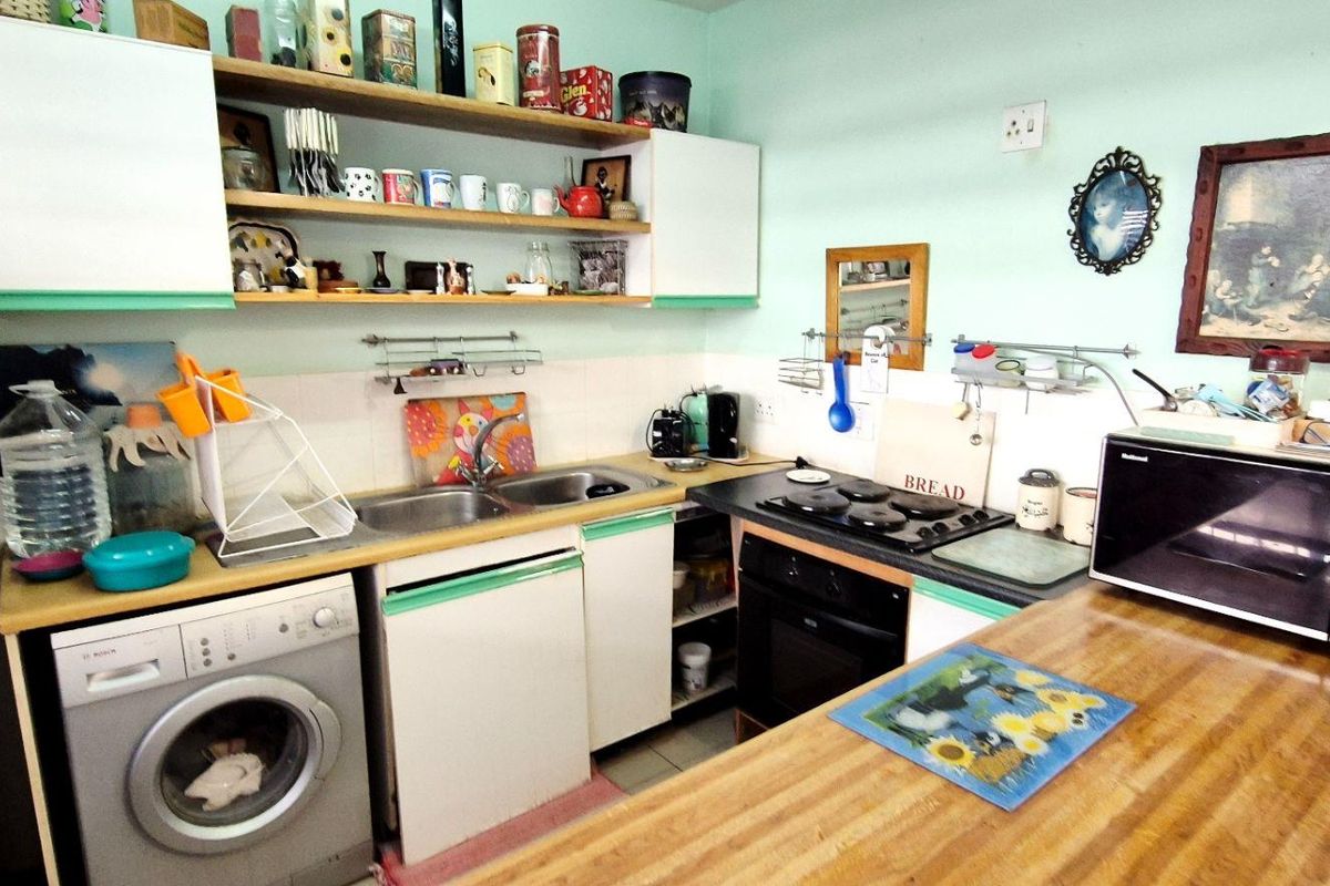 A functional kitchen featuring built-in cabinetry, a gas hob, an integrated oven, and a dedicated space for a washing machine.