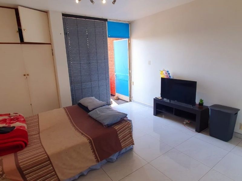 A bedroom featuring tiled flooring, a built-in wardrobe with a damaged door, and direct access to an outdoor area.